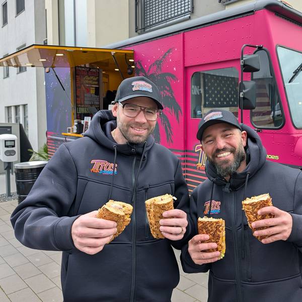 Das Foto zeigt die beiden Betreiber mit Baguettes vor dem Foodtruck.
