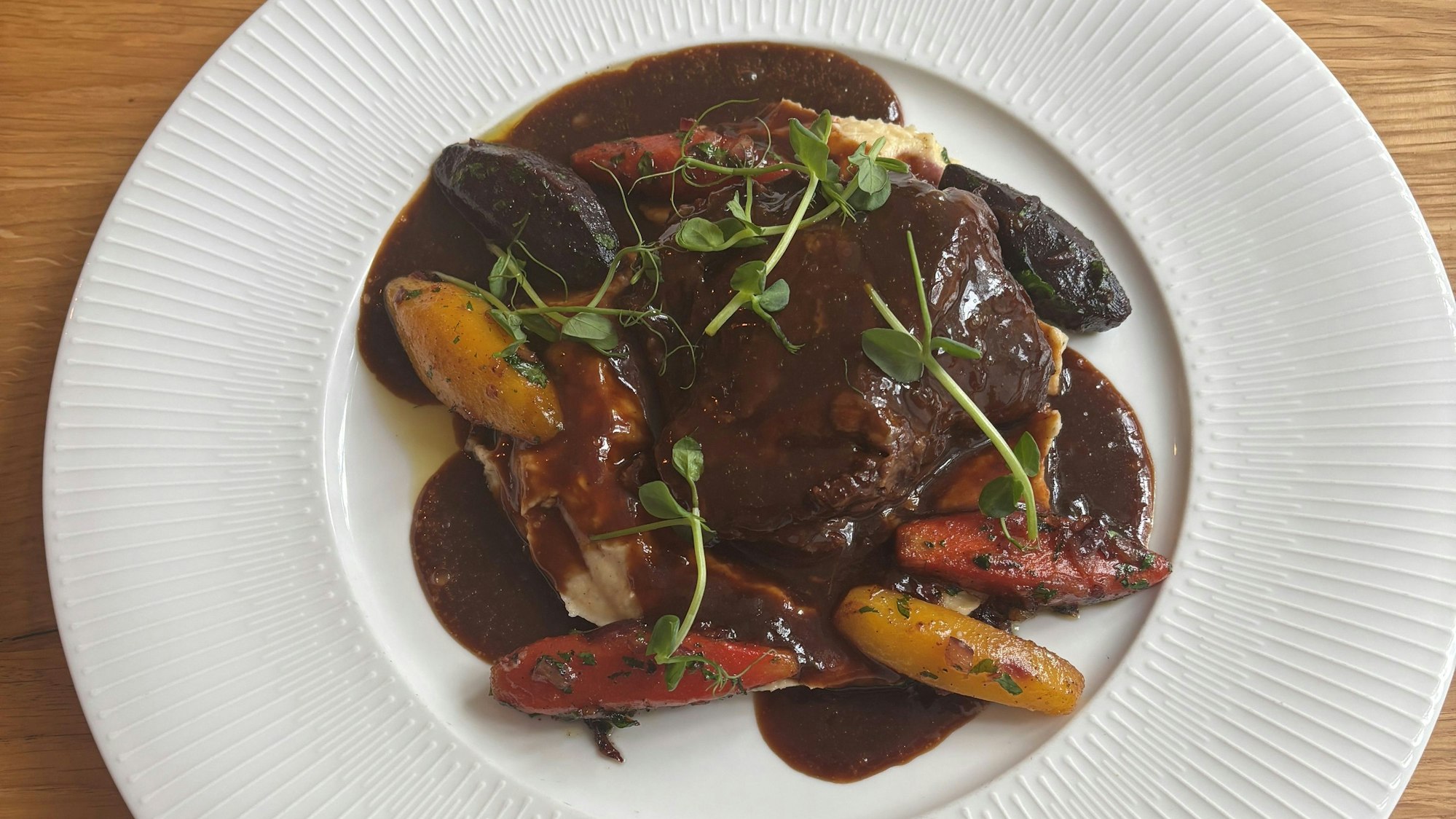 Das Bild zeigt das Gericht auf einem weißen Teller, die Soße ist braun.