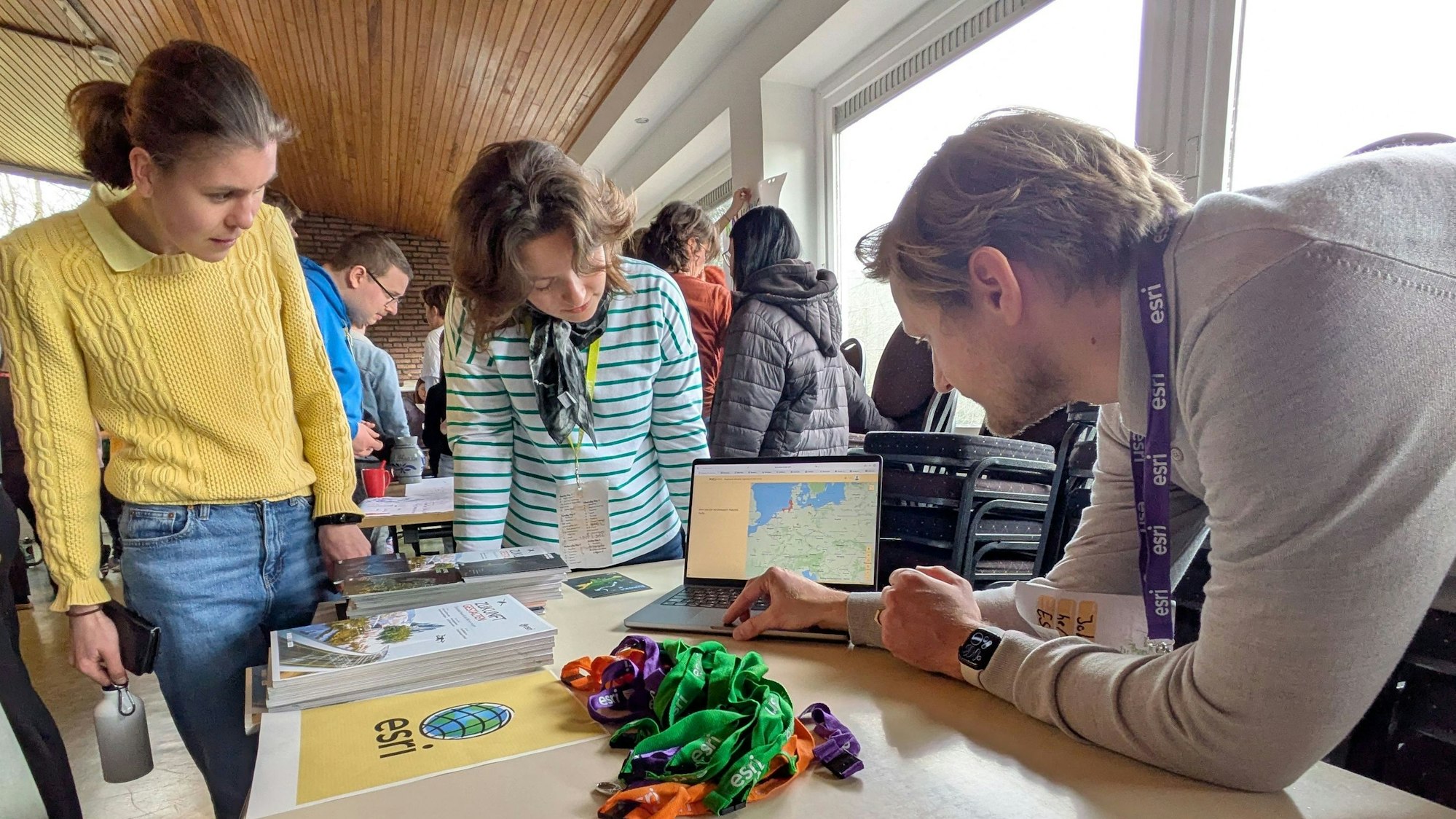 Zwei Frauen und ein Mann schauen während einer Präsentation auf den Bildschirm eines Laptops