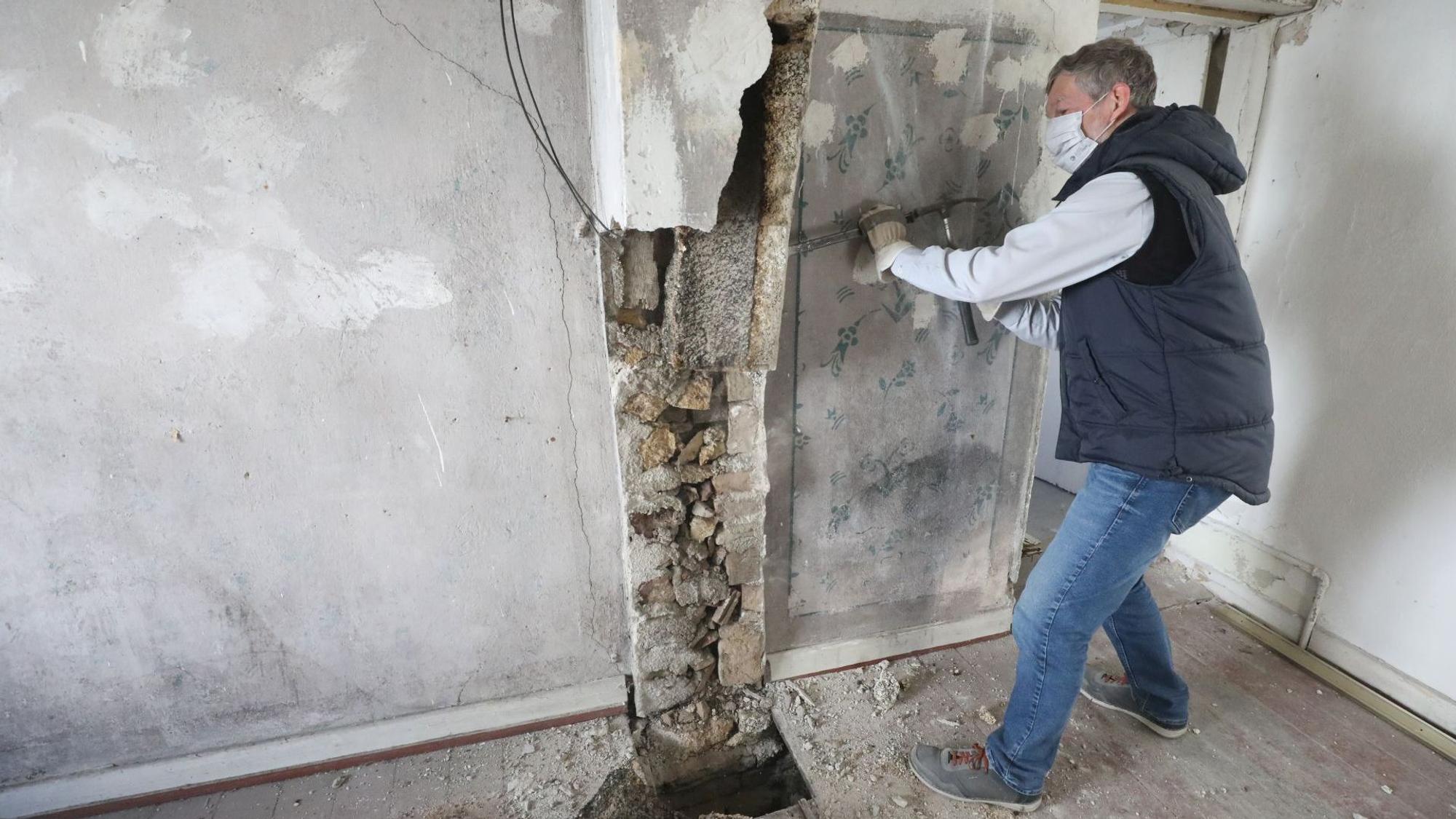 Ein Mann mit Mundschutz arbeitet mit Hammer und Meißel.