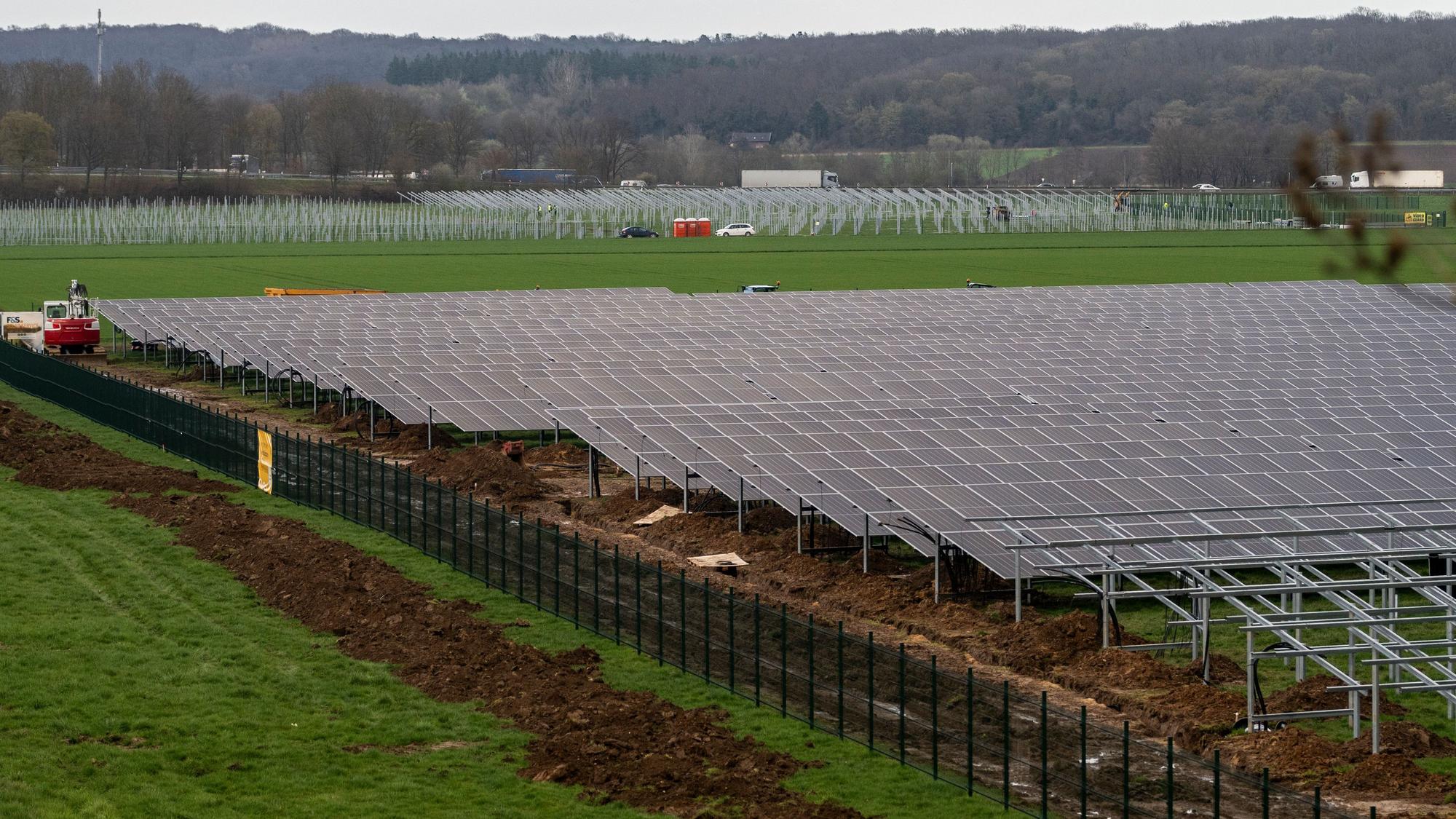 Hinter eine Zaum werden gerade Solarpaneele montiert.