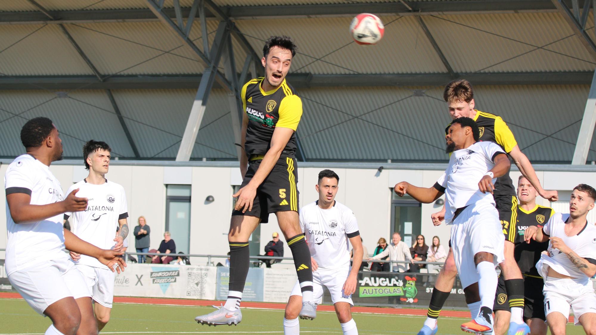 Mehrere Spieler versuchen, den Ball mit dem Kopf zu erreichen, andere beobachten die Szene..