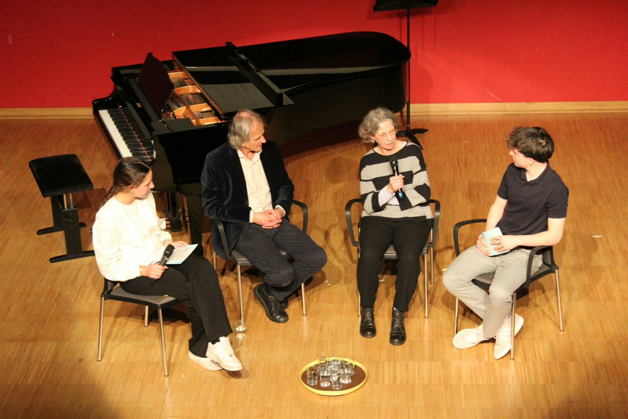 Das Bild zeigt die vier Personen sitzend auf der Bühne.