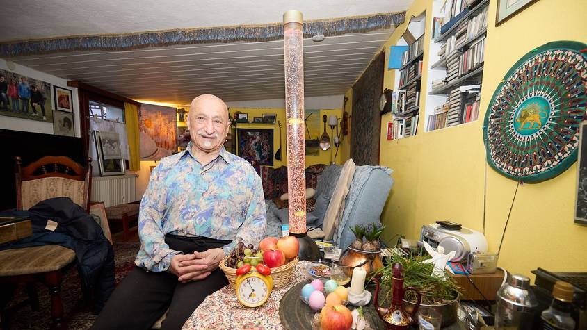 Hassan Deldjoue Shahir sitzt an einem Tisch, auf dem er Dinge arrangiert hat, die Glück und Gesundheit symbolisieren sollen.