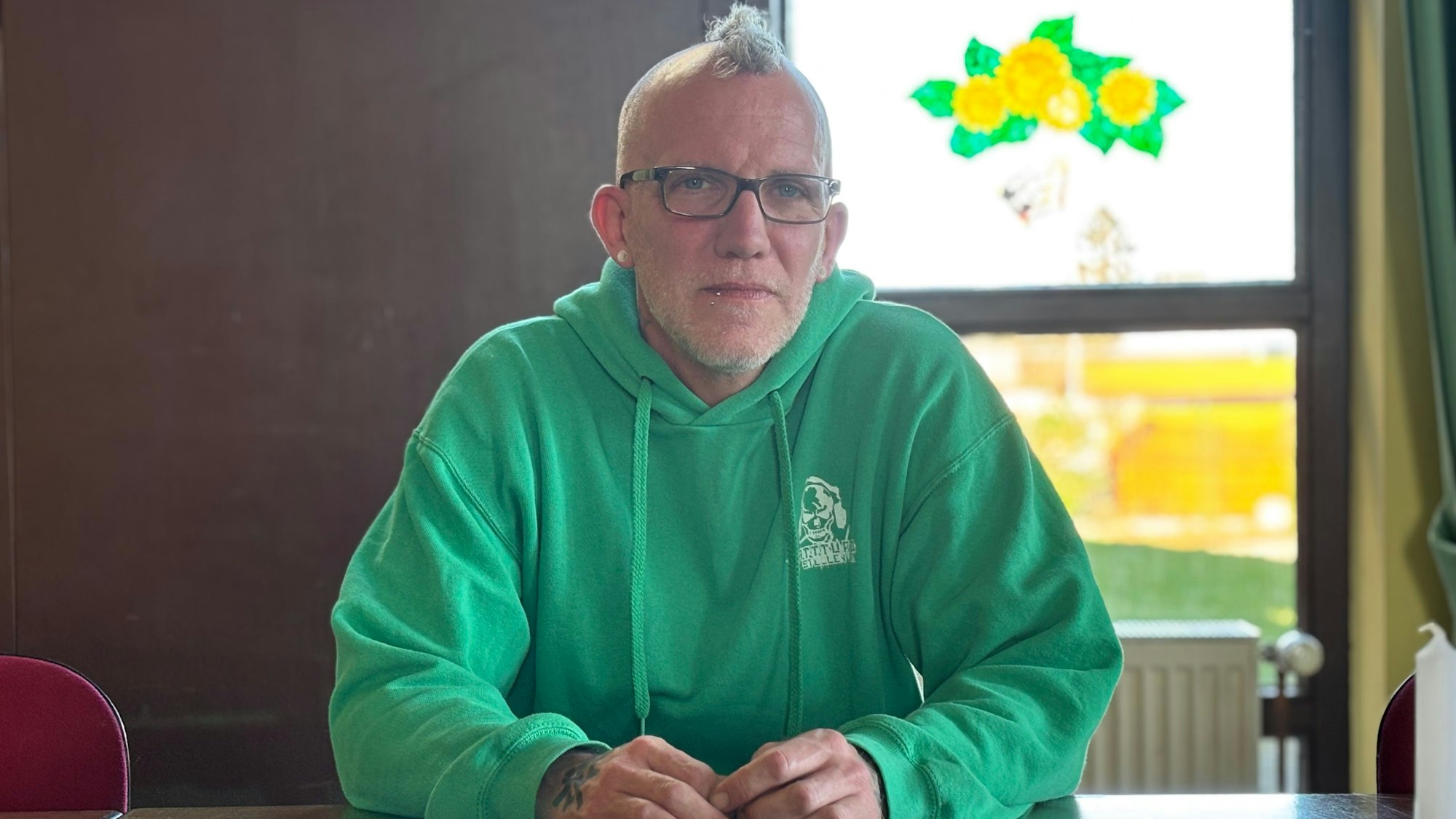 Martin Oertel trägt Brille, Hoodie und Iro. Er sitzt in einem Raum und wird von natürlichem Licht angeleuchtet.