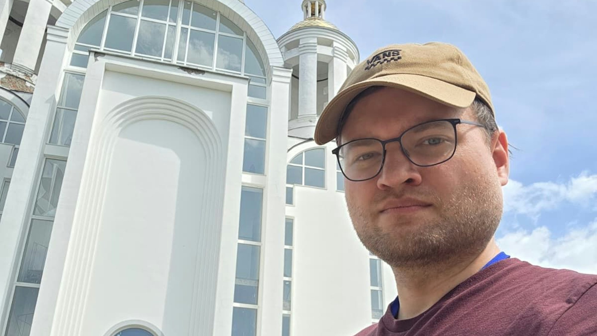 Michael Stadnik trägt eine beige Kappe, eine schwarze Brille und einen kurzen Dreitagebart.