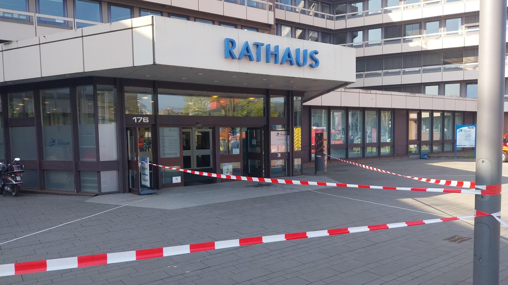 Rot-Weißes Absperrband hängt vor dem Eingangsbereich des Troisdorfer Rathauses.