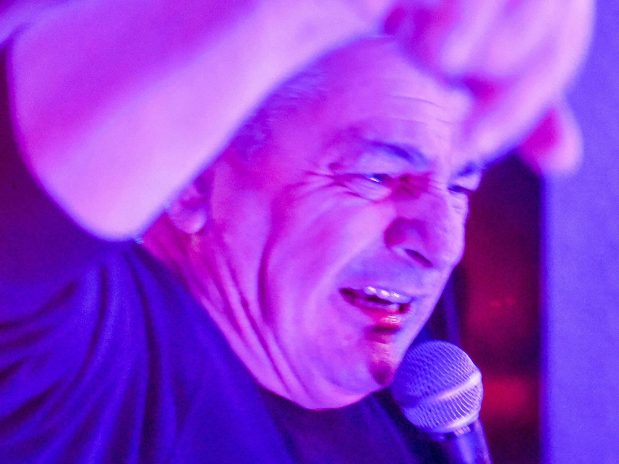 Auf dem Bild ist ein Sänger mit einem Mikrophon zu sehen.