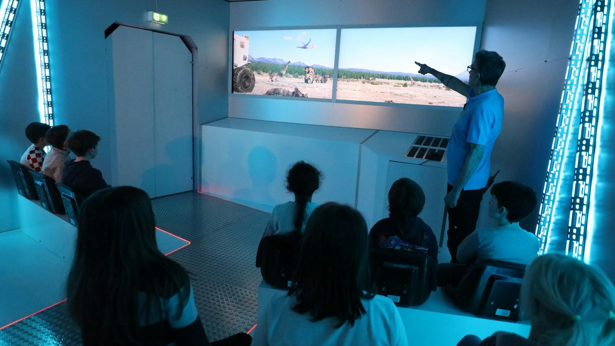 Kinder vor zwei großen Bildschirmen.