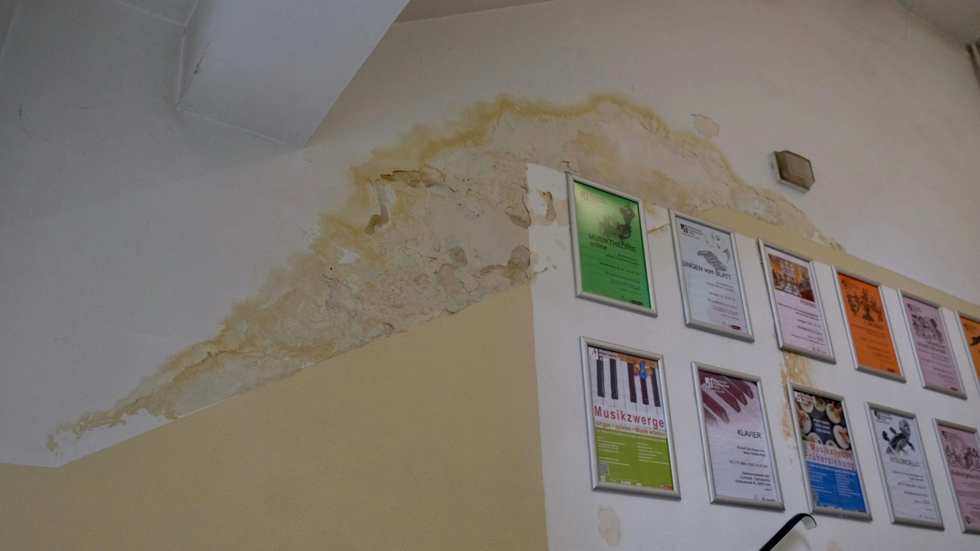 Ein Wasserschaden zeichnet sich an einer Decke und Wand eines Gebäudes ab.