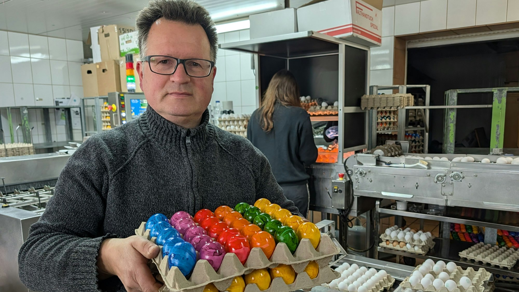 Das Foto zeigt Martin Füngeling mit zwei Lagen gefärbter Eier im Produktionsbereich des Eierhofs.