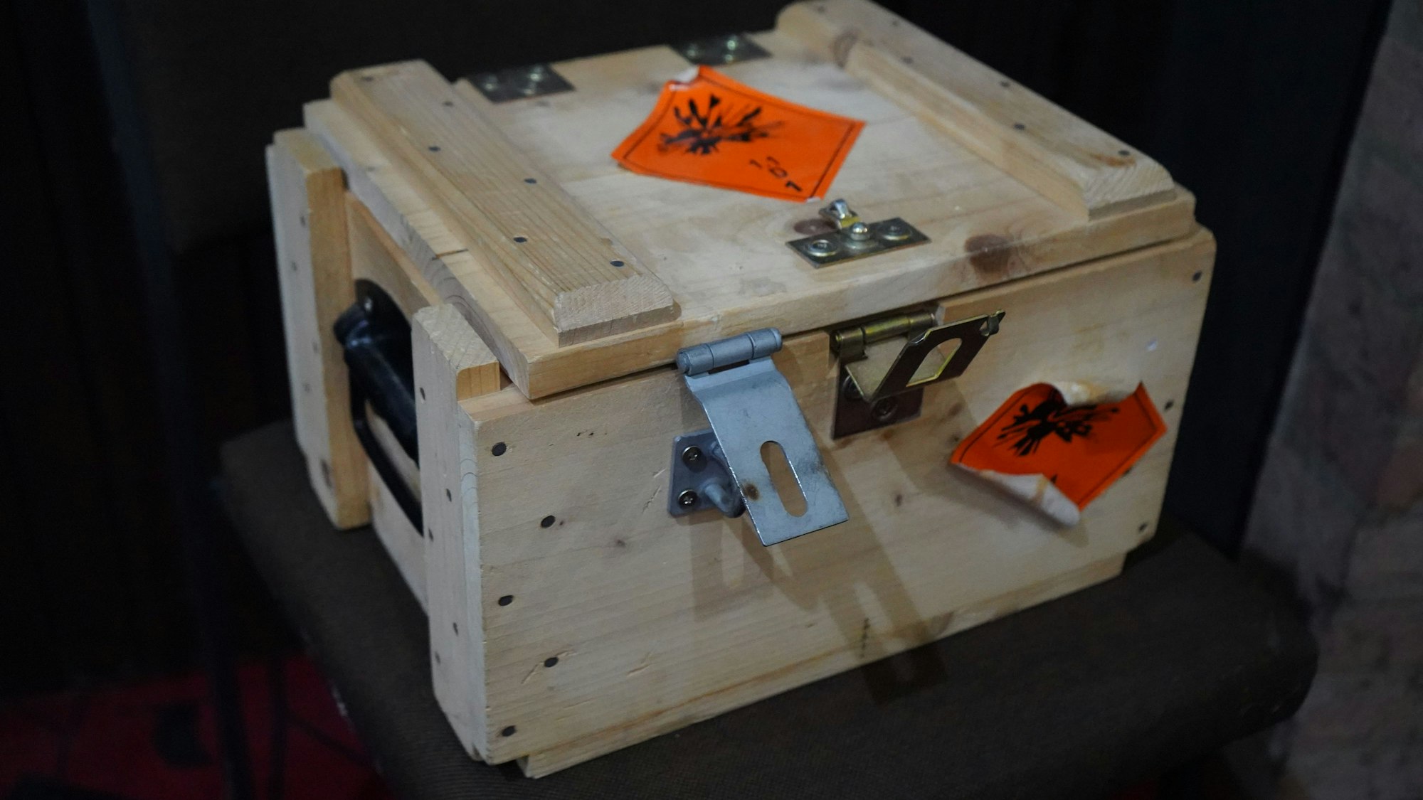 Das Bild zeigt eine Holzkiste mit Gefahrenlogos.
