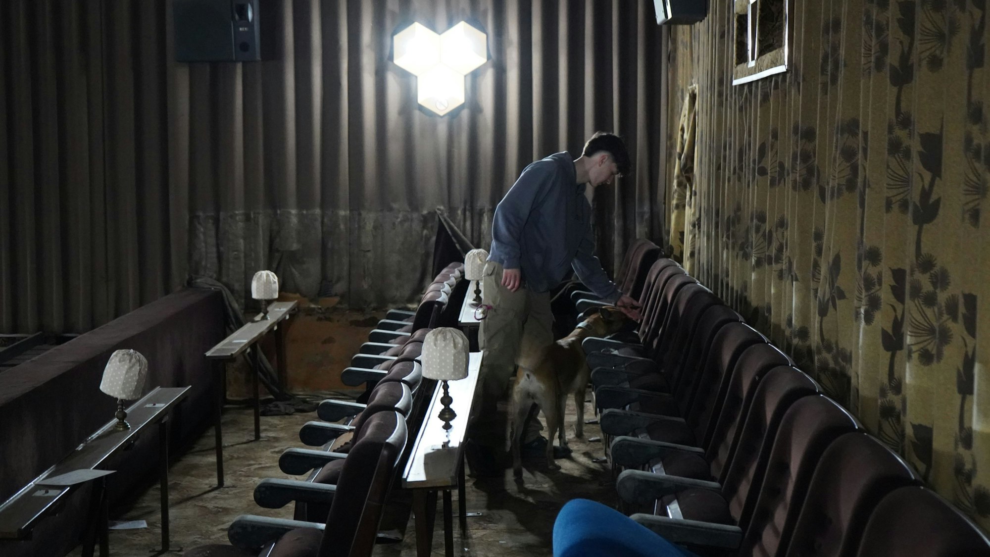 Das Bild zeigt Hundeführer und Hund zwischen den Sitzreihen im Kino.