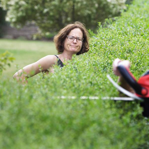 Ein Mann schneidet eine Hecke.