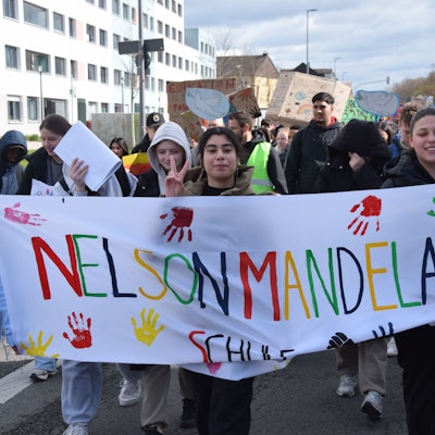 Schülerinnen und Schüler tragen ein Transparent, auf dem Nelson-Mandela-Schule steht.