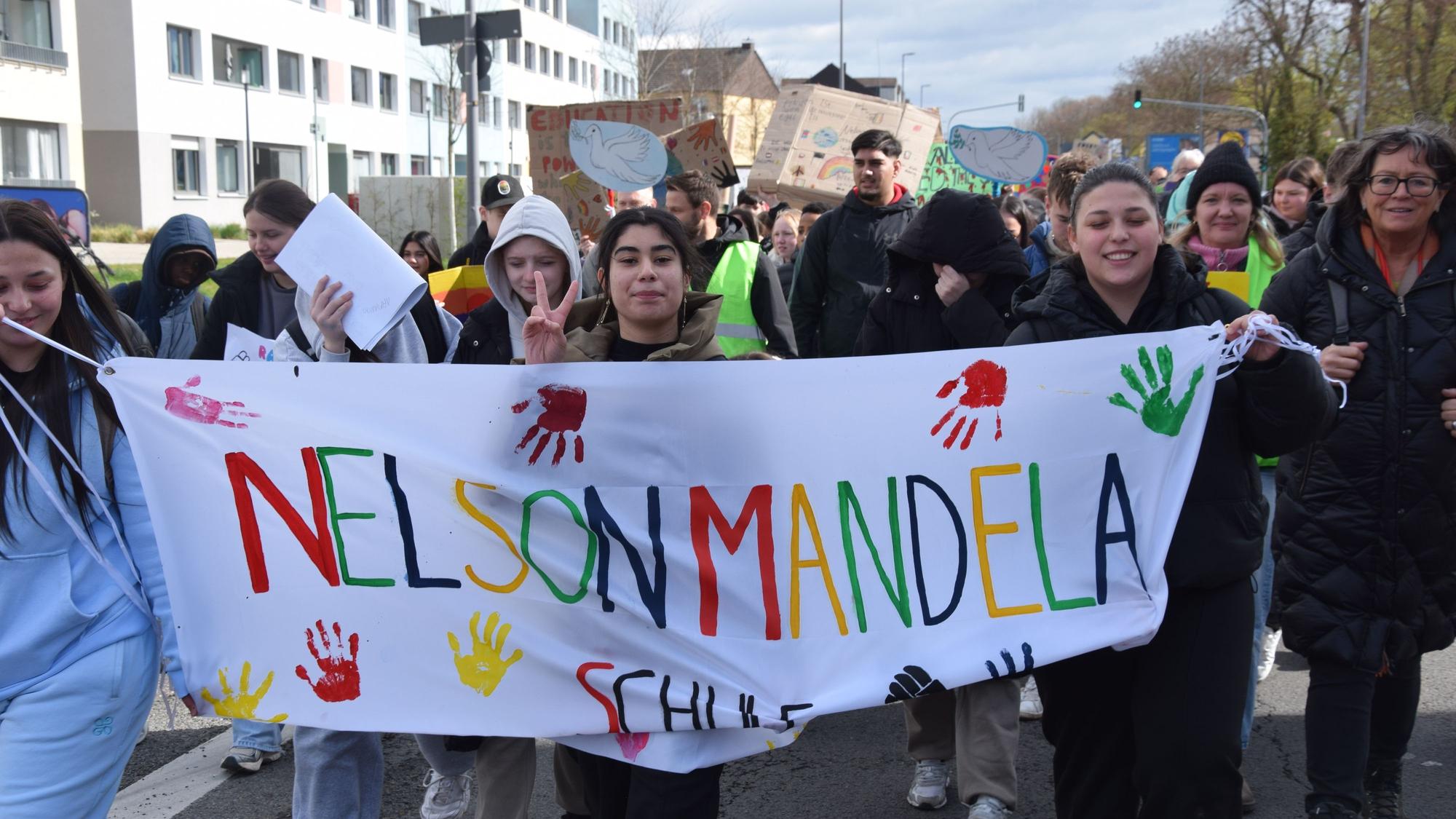Schülerinnen und Schüler tragen ein Transparent, auf dem Nelson-Mandela-Schule steht.