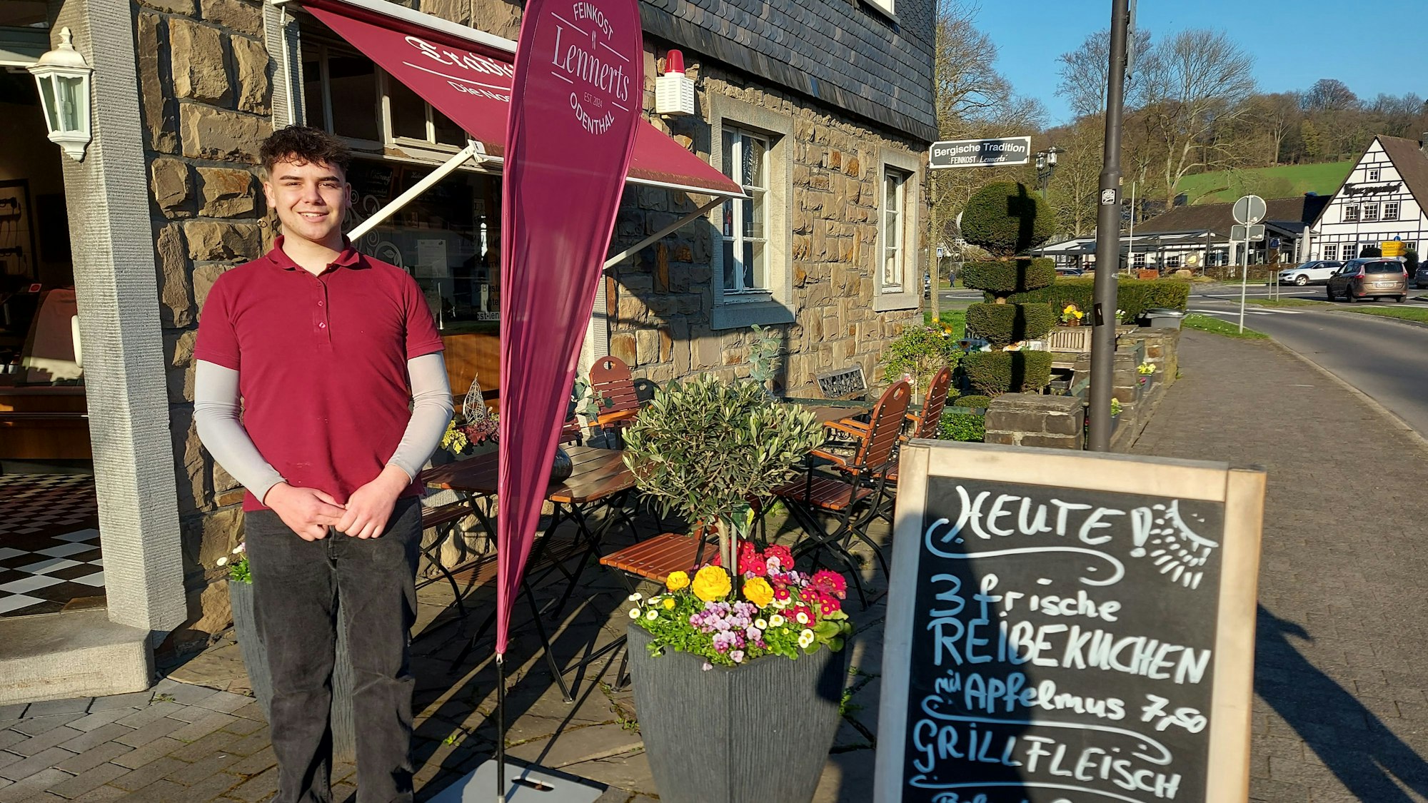 Ein junger Mann steht vor einer kleinen Landmetzgerei.