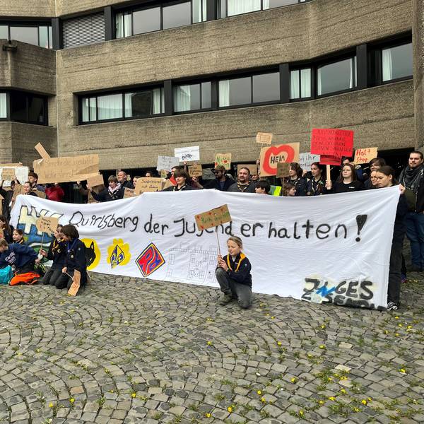 Mit Plakaten und einem großen Transparent stehen die Demonstranten vor dem Eingang zum Rathaus.