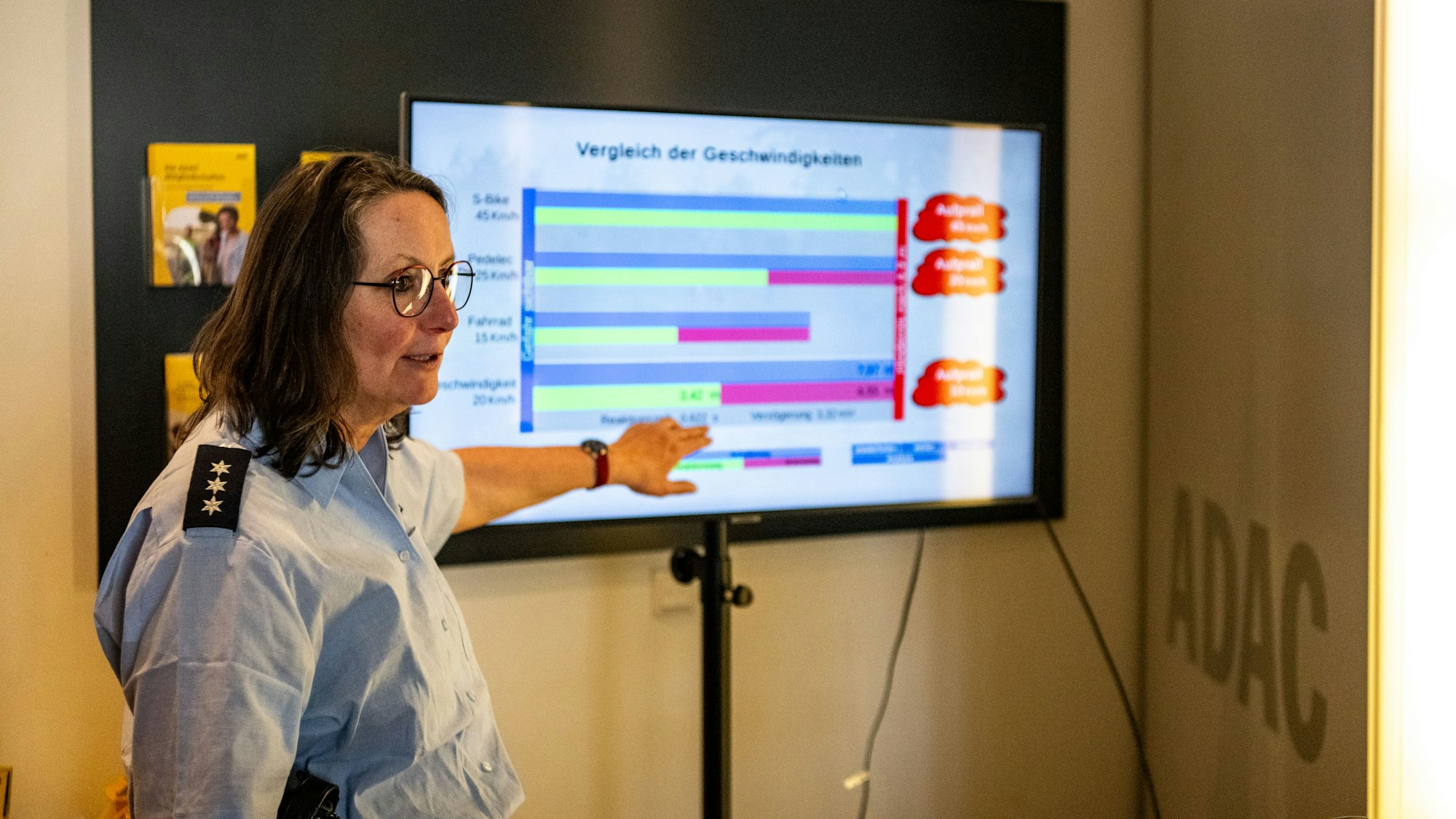 Das Bild zeigt eine Polizeibeamtin, die an einem Monitor die Ergebnisse der Simumaltion erklärt.