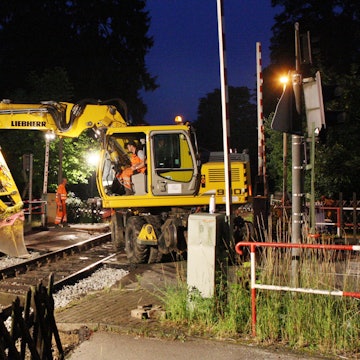 Bahnbauarbeiter arbeiten mit einem Bagger am Bahnübergang Gerottener Weg in Rösrath am Gleis der Regionalbahnstrecke 25.