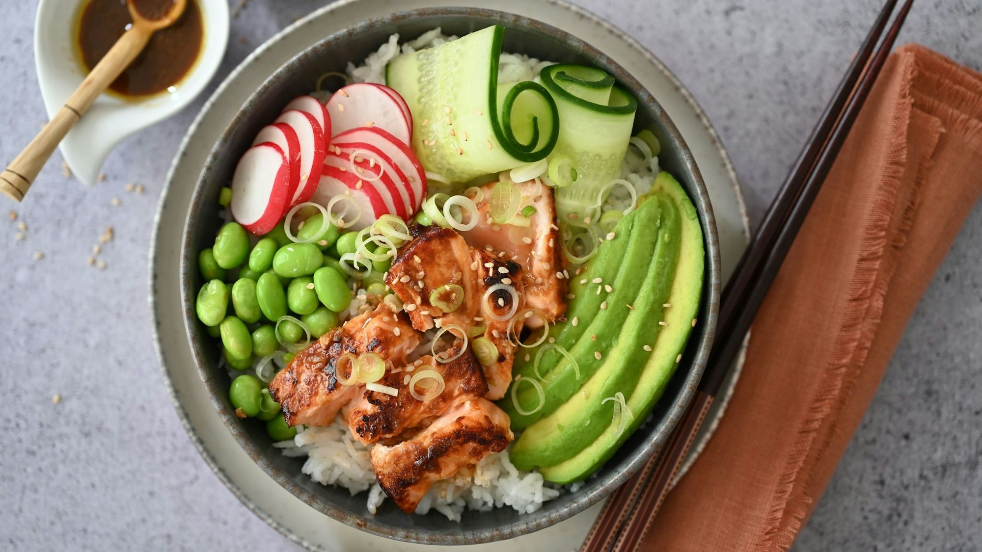 Bowl mit mariniertem und glasiertem Lachs und knackigem Gemüse auf Reis.