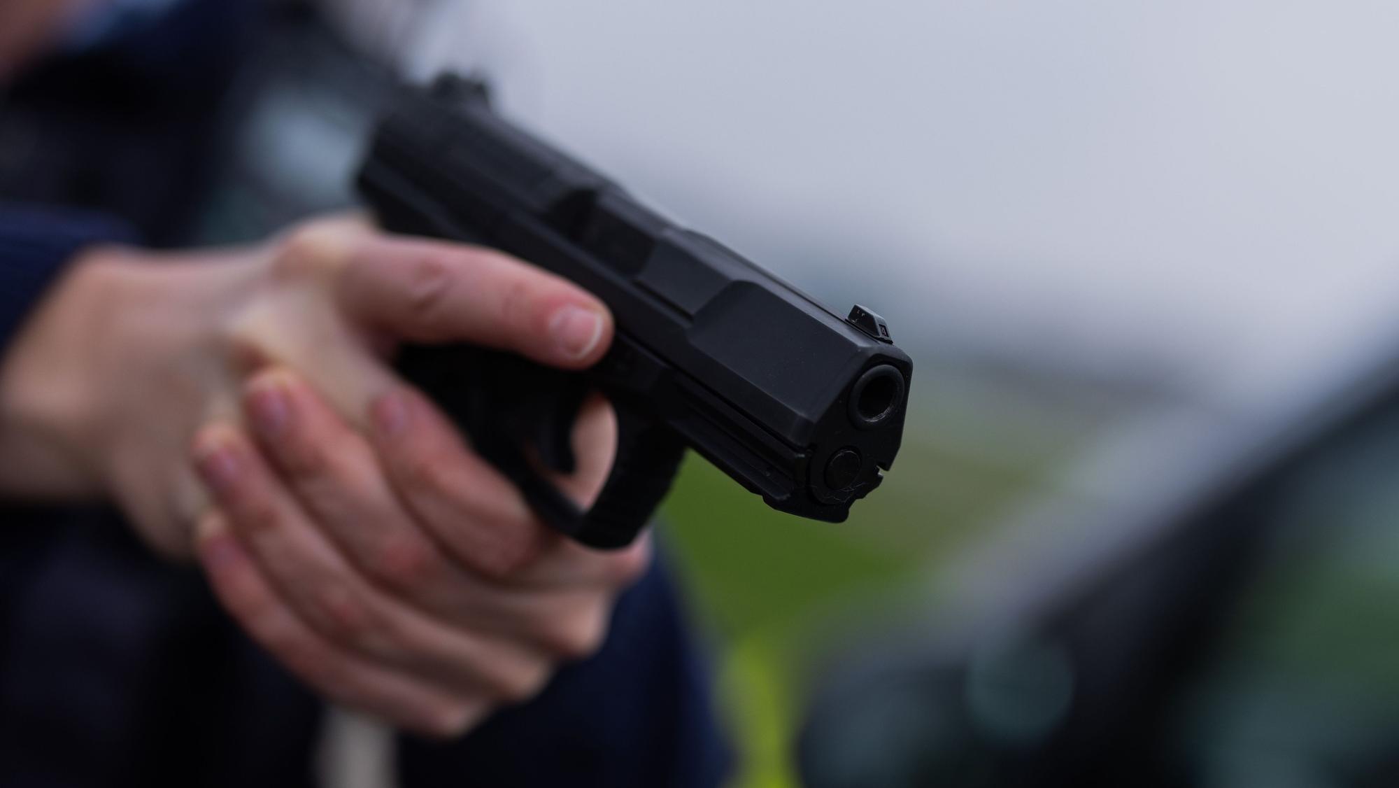 Ein Mann hält eine schwarze Pistole in den Händen.