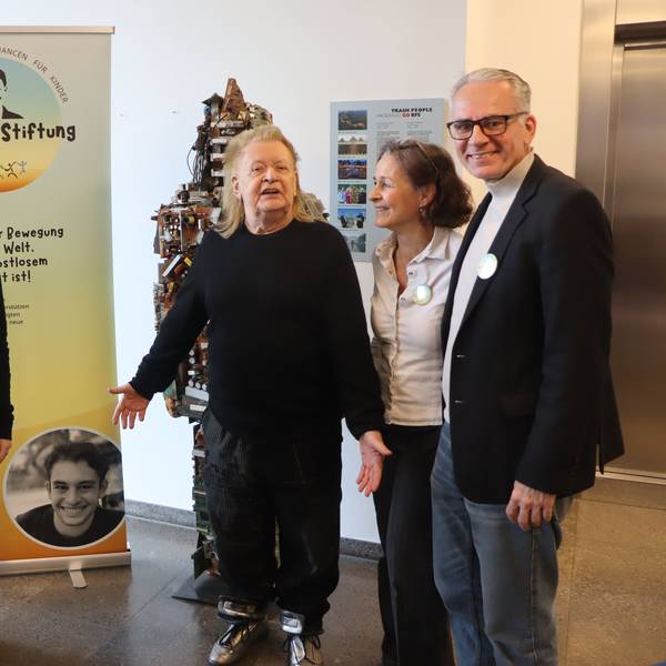 Auf dem Foto ist eine Familie mit dem Künstler HA Schult zu sehen.