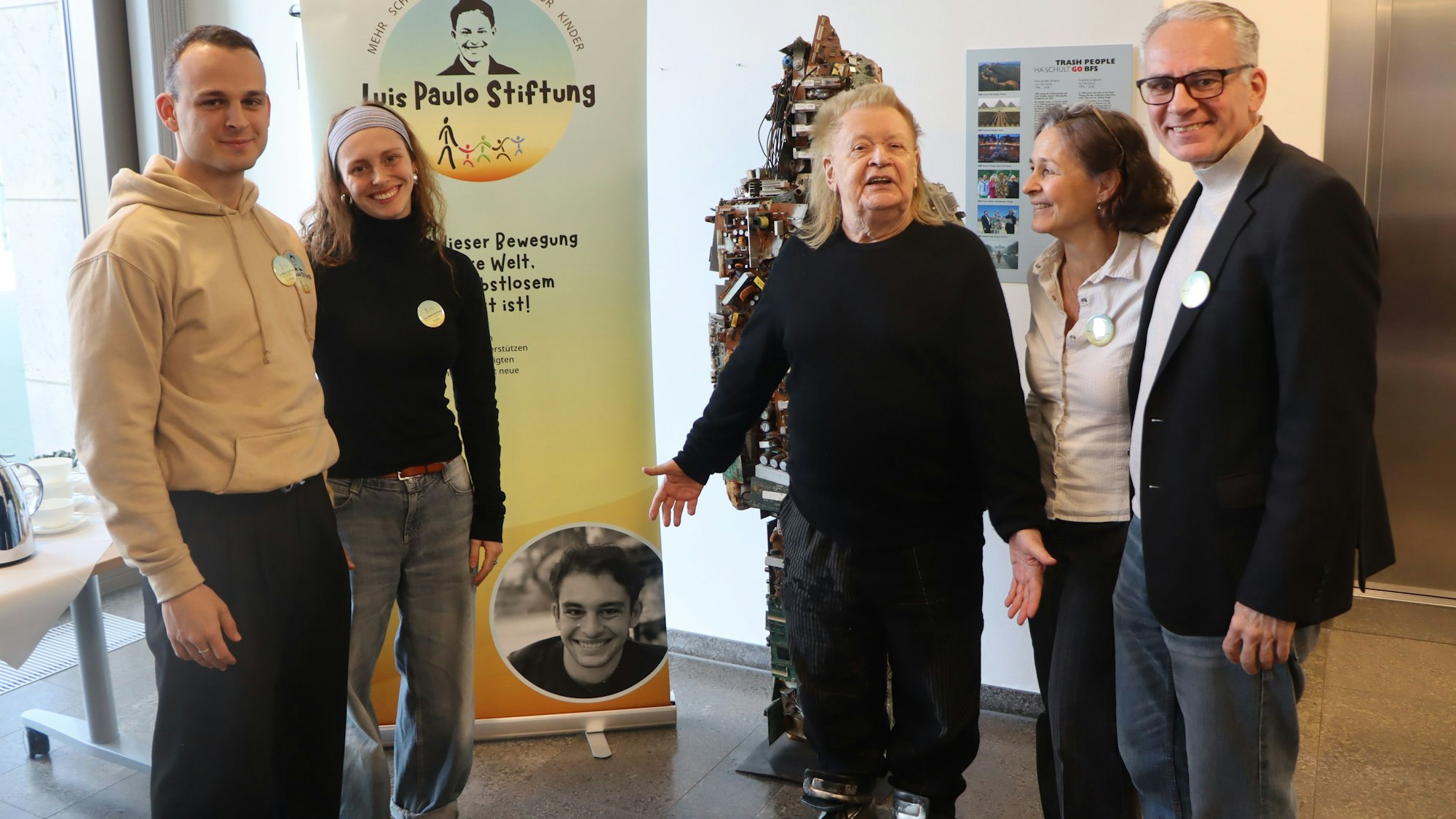 Auf dem Foto ist eine Familie mit dem Künstler HA Schult zu sehen.