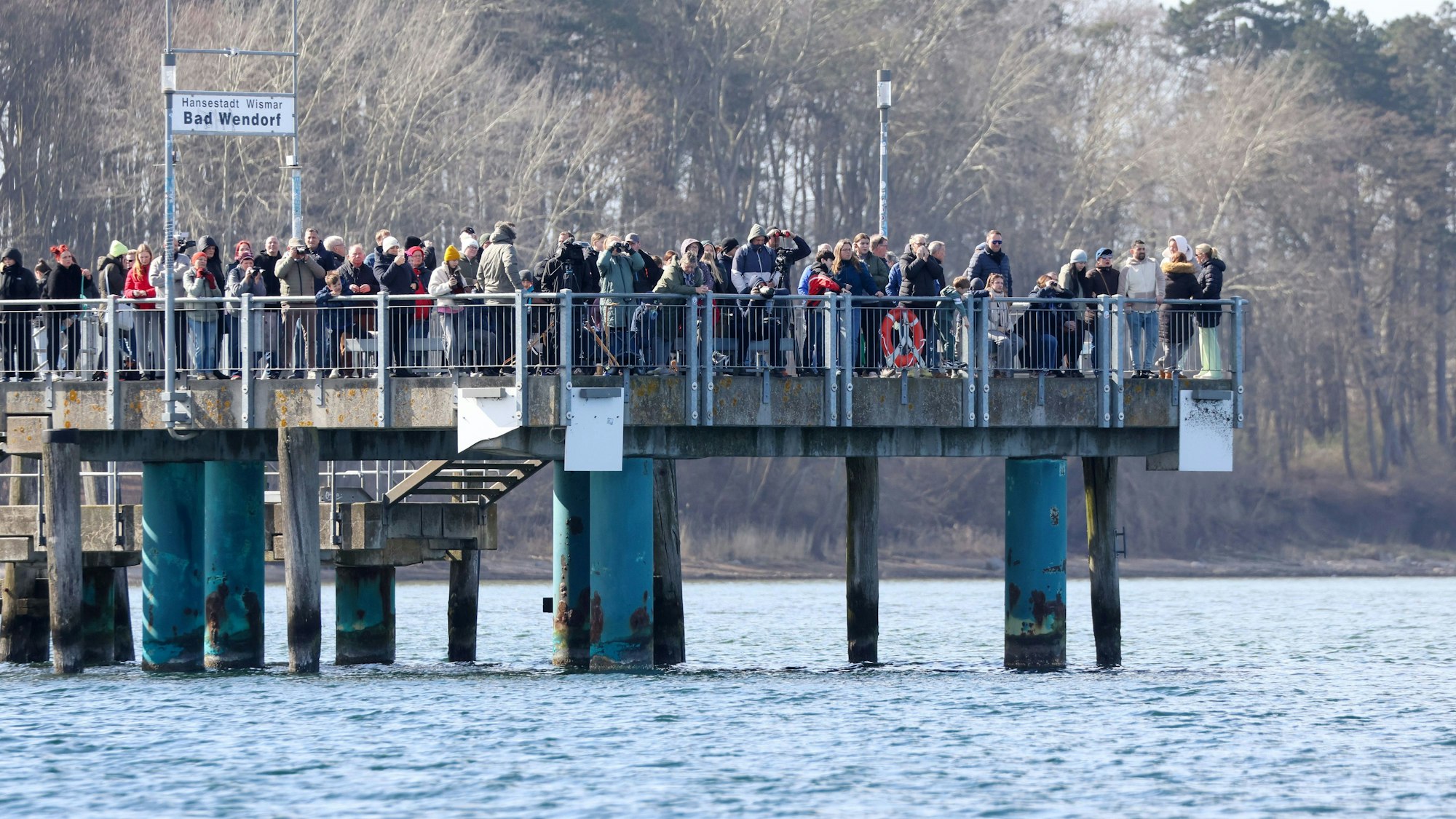 Schaulustige stehen am Sonntagnachmittag auf der Seebrücke in Wismar. Der vor rund einer Woche bei Timmendorfer Strand an der Ostseeküste gestrandete Buckelwal liegt noch immer in der Wismarbucht.