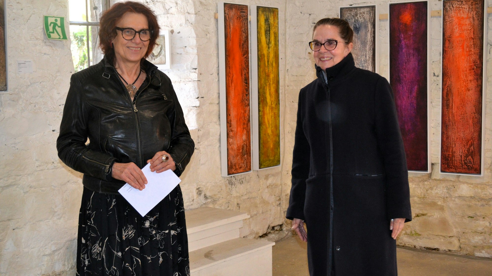 Die beiden Frauen stehen nebeneinander und lächeln.