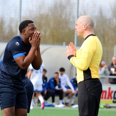 Kuss Kunzika faltet fassungslos die Hände vors Gesicht, während der Schiedsrichter mit ihm über eine Entscheidung spricht.