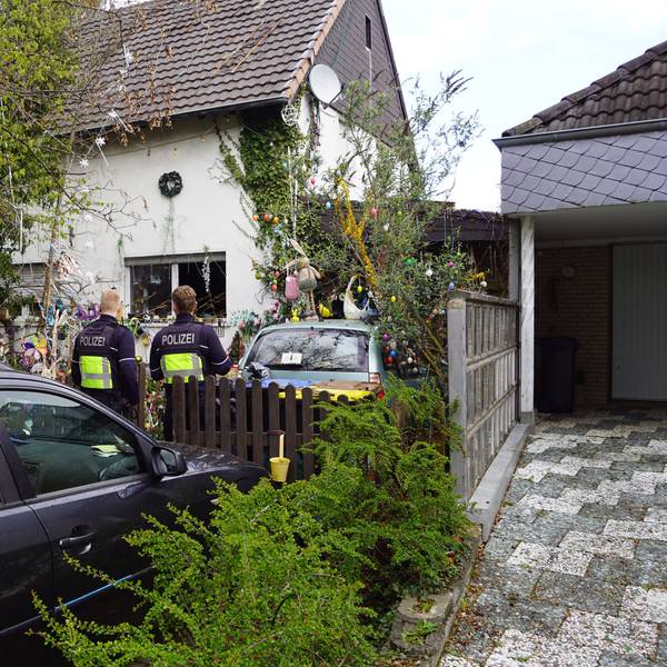 Zwei Polizisten stehen an einem Haus in Euskirchen-Billig, in dem es zu einer Verpuffung gekommen war.