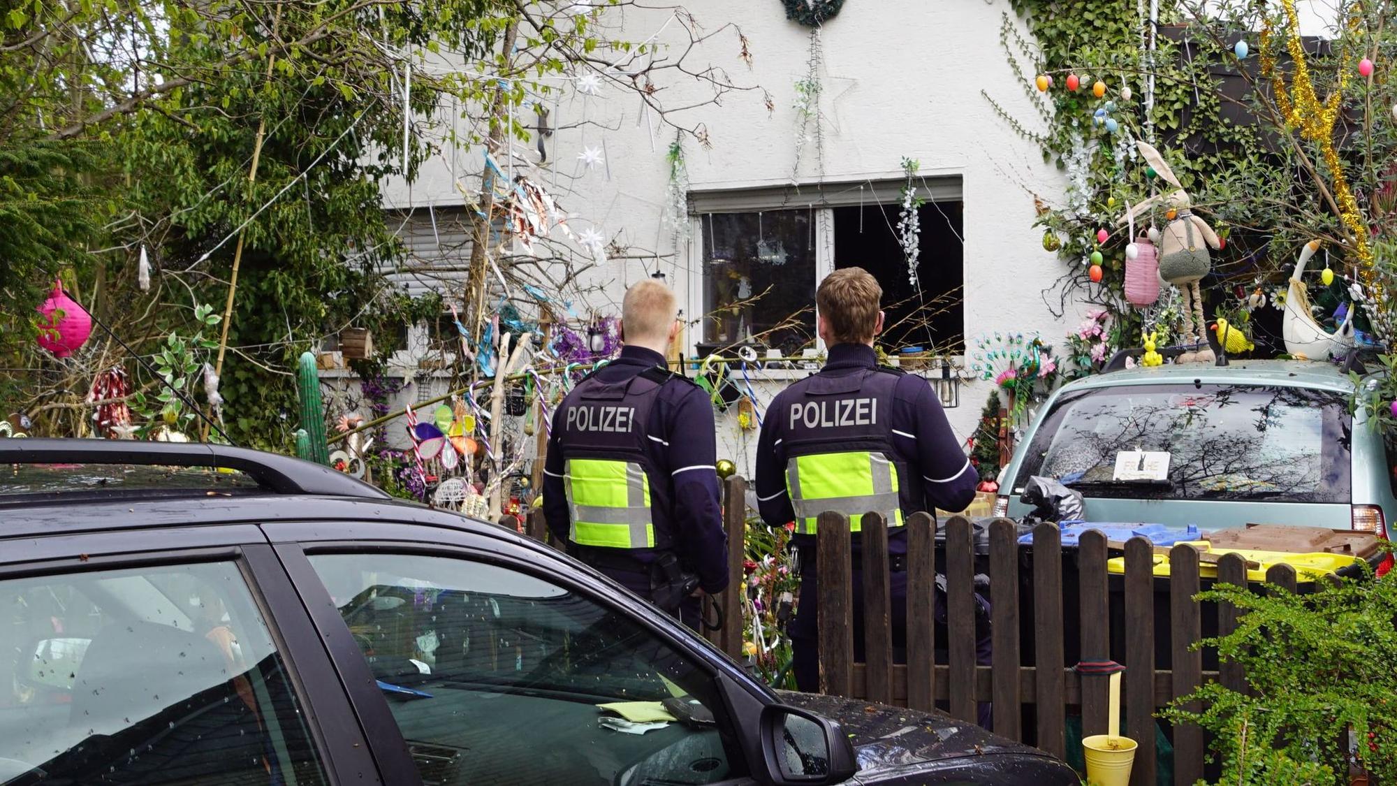 Zwei Polizisten stehen an einem Haus in Euskirchen-Billig, in dem es zu einer Verpuffung gekommen war.