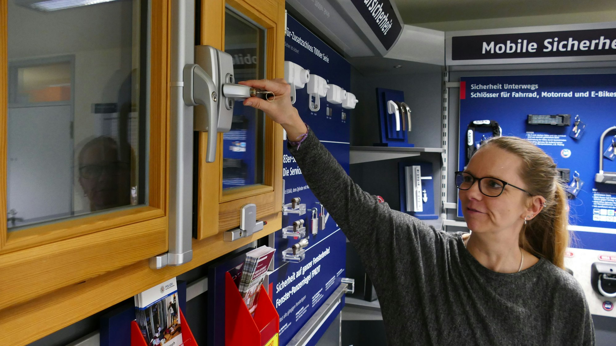 Eine Frau steht vor einem Fenster und berührt den Griff mit ihrer Hand.