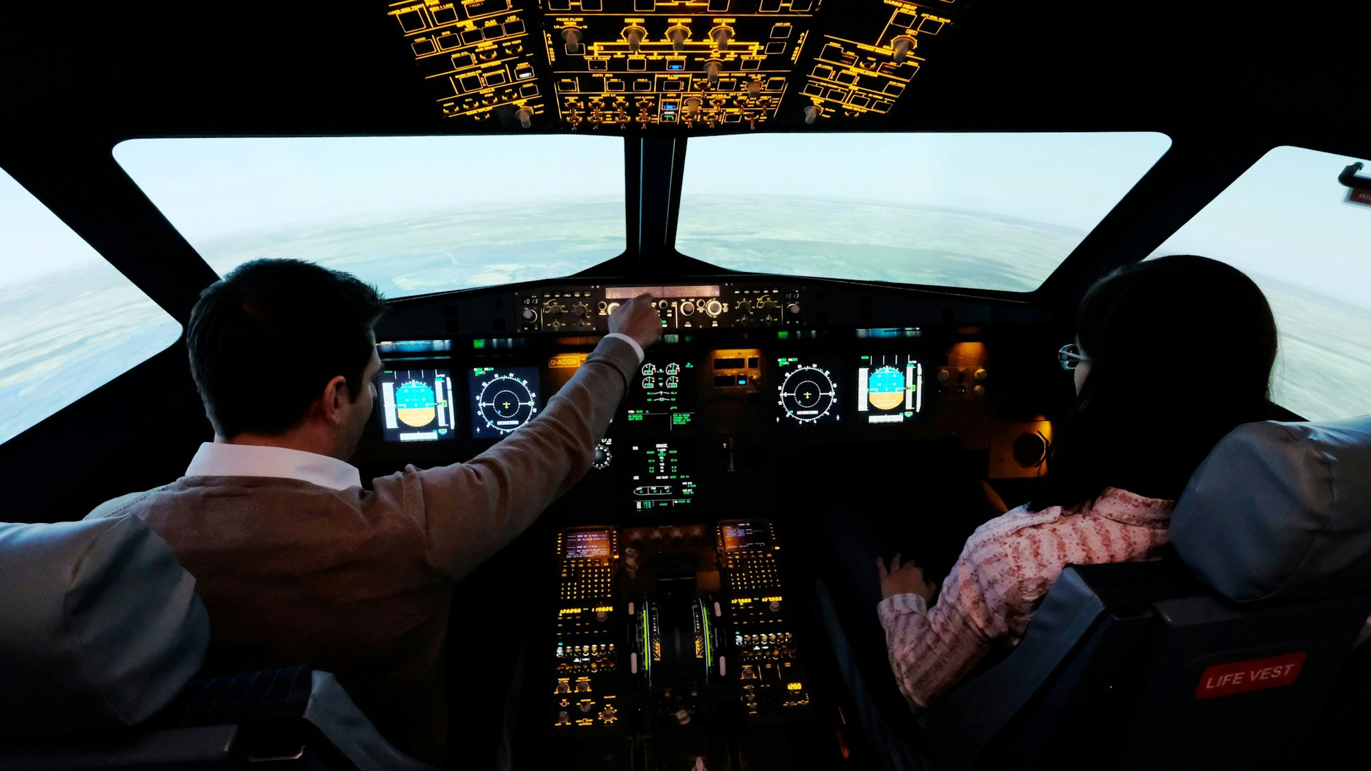 Zwei Personen sitzen in einem Flugsimulator.