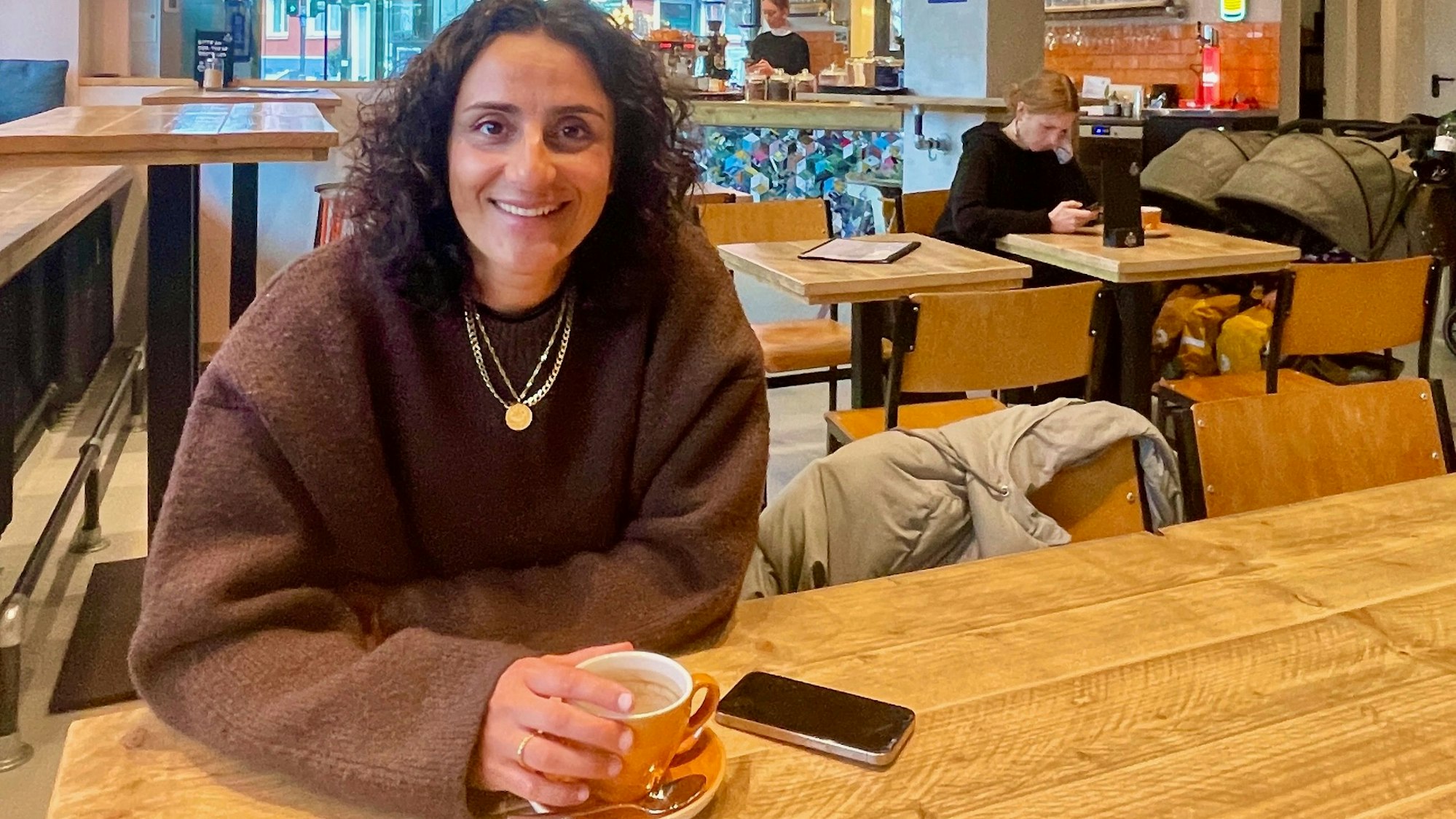 Eine Frau sitzt in einem Café und trinkt Cappuccino.