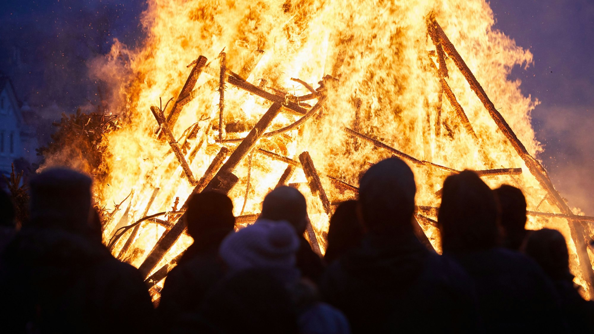 Menschen stehen vor einem Osterfeuer.