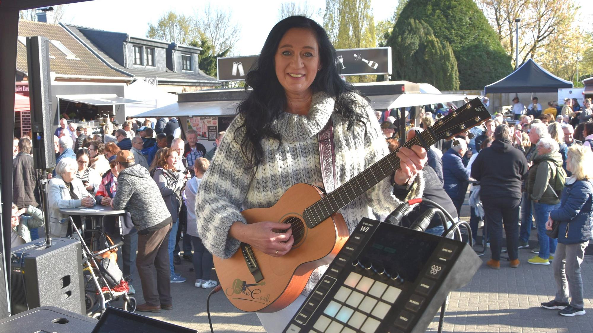 Eine Frau mit Gitarre steht auf einer Bühne.