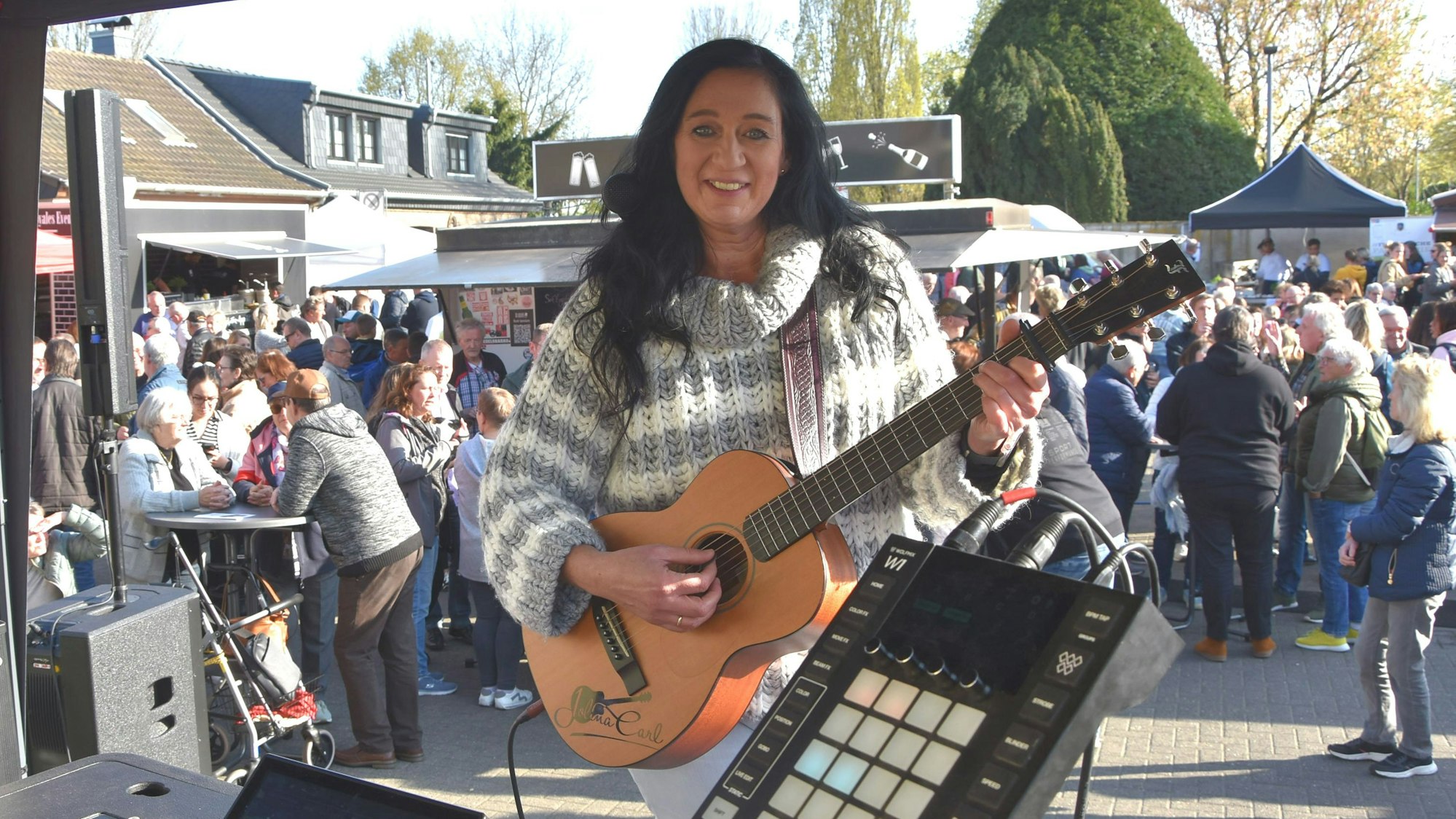 Eine Frau mit Gitarre steht auf einer Bühne.