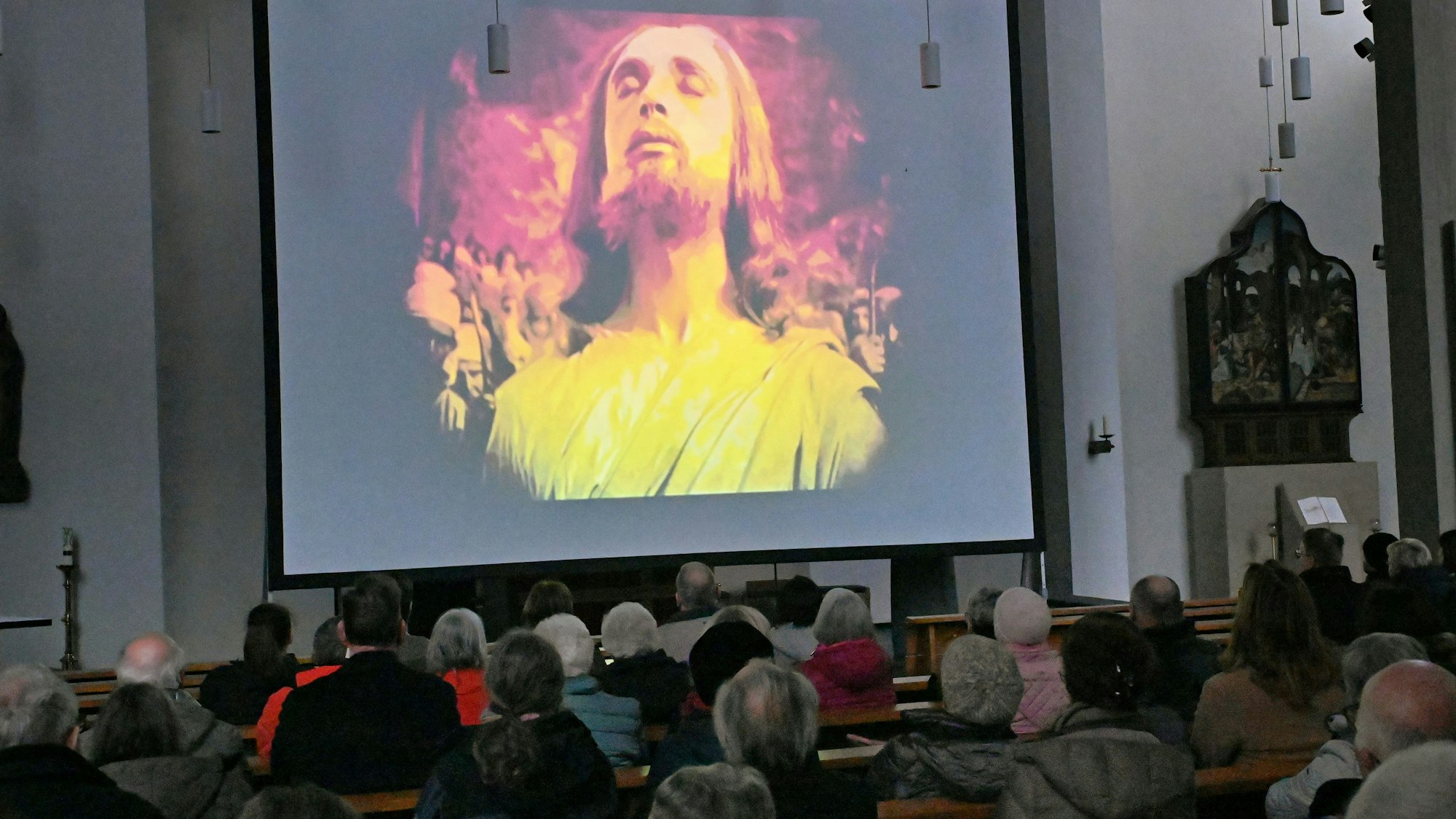 Auf einer großen Leindwand ist in einer Filmszene das Gesicht Jesu zu sehen.