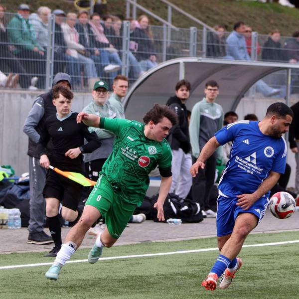 Zwei Fußballer laufen nach vorne, blicken aber zurück, weil sich der Ball hinter ihnen befindet.