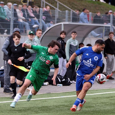 Zwei Fußballer laufen nach vorne, blicken aber zurück, weil sich der Ball hinter ihnen befindet.