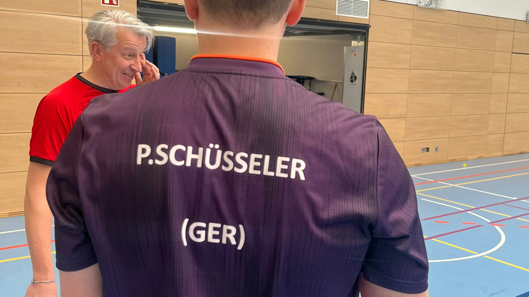 Patrick Schüsseler steht mit dem Rücken zur Kamera. Auf dem Trikot steht sein Name. Im Hintergrung ist Frank Weinberg zu sehen.