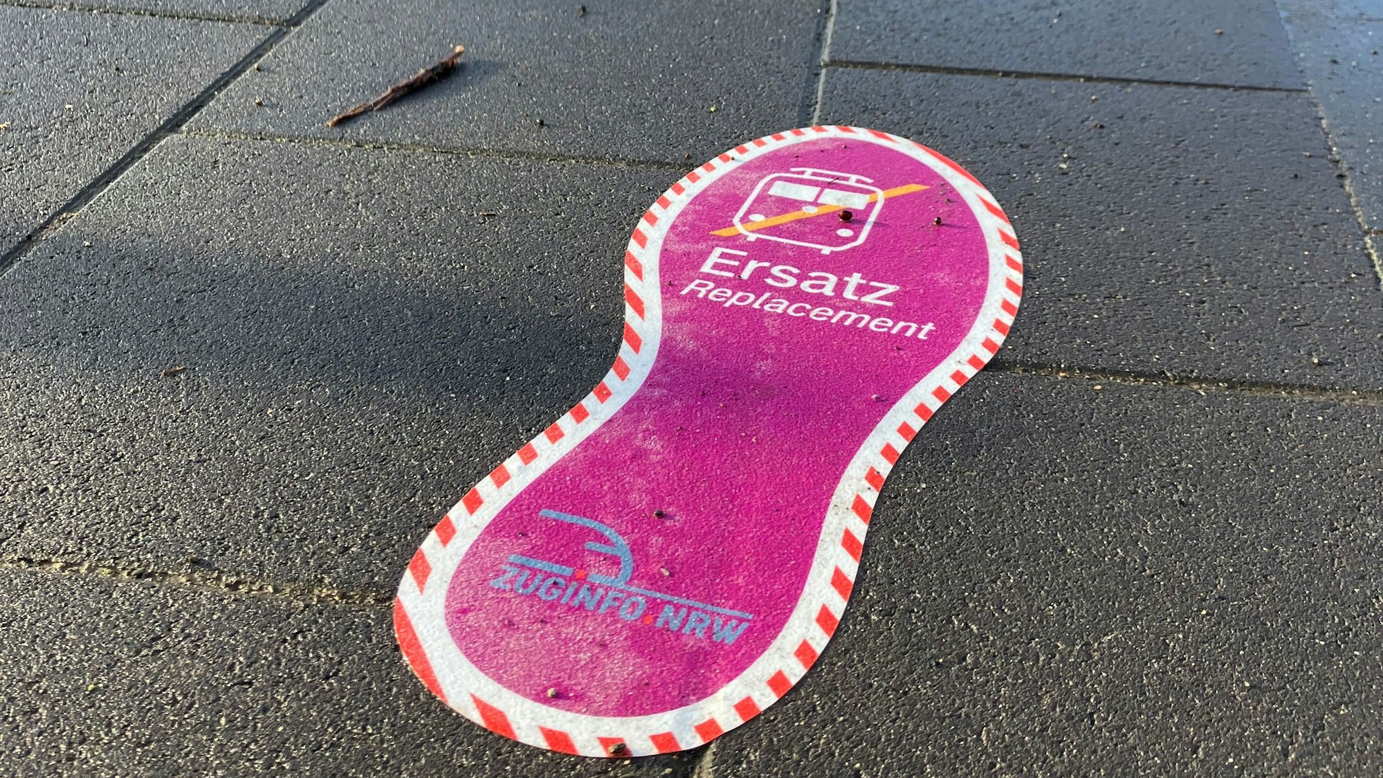 Ein Schuhabdruck im markanten SEV-Violett kelbt auf einem Gehweg.