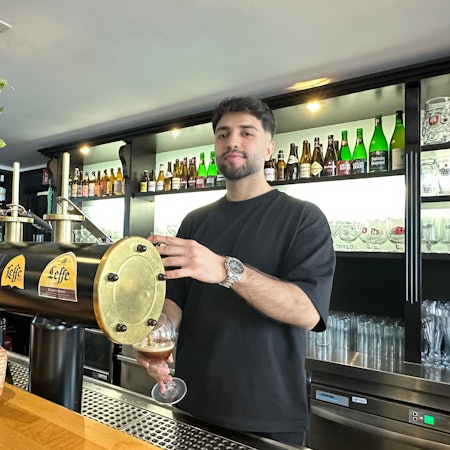 Ein junger Mann zapft ein Bier an einer Brauhaus-Theke.