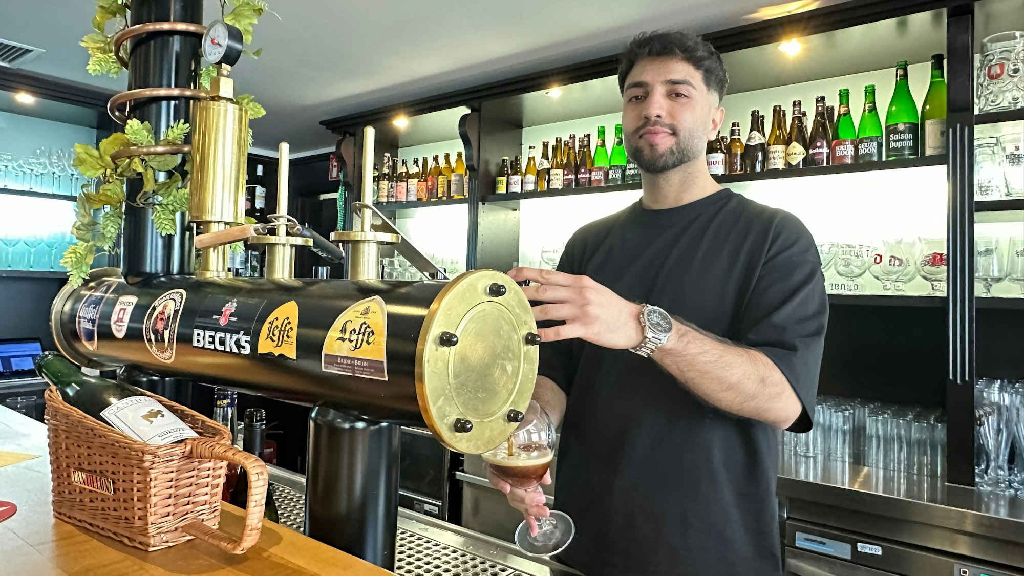 Ein junger Mann zapft ein Bier an einer Brauhaus-Theke.