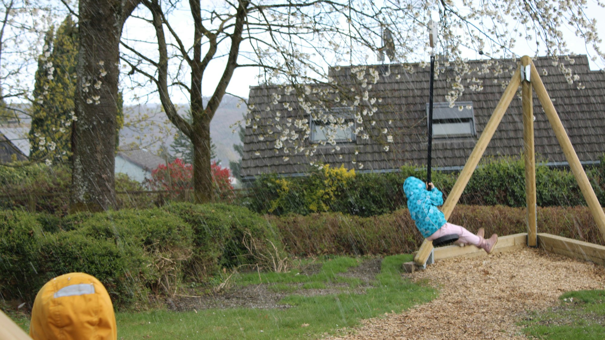 Kinder sind mit Regenjacke auf der Seilbahn.