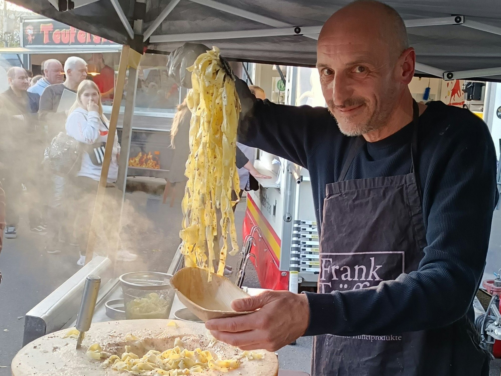 Ein Mann füllt Pasta aus einem Parmesanlaib in eine Schale.