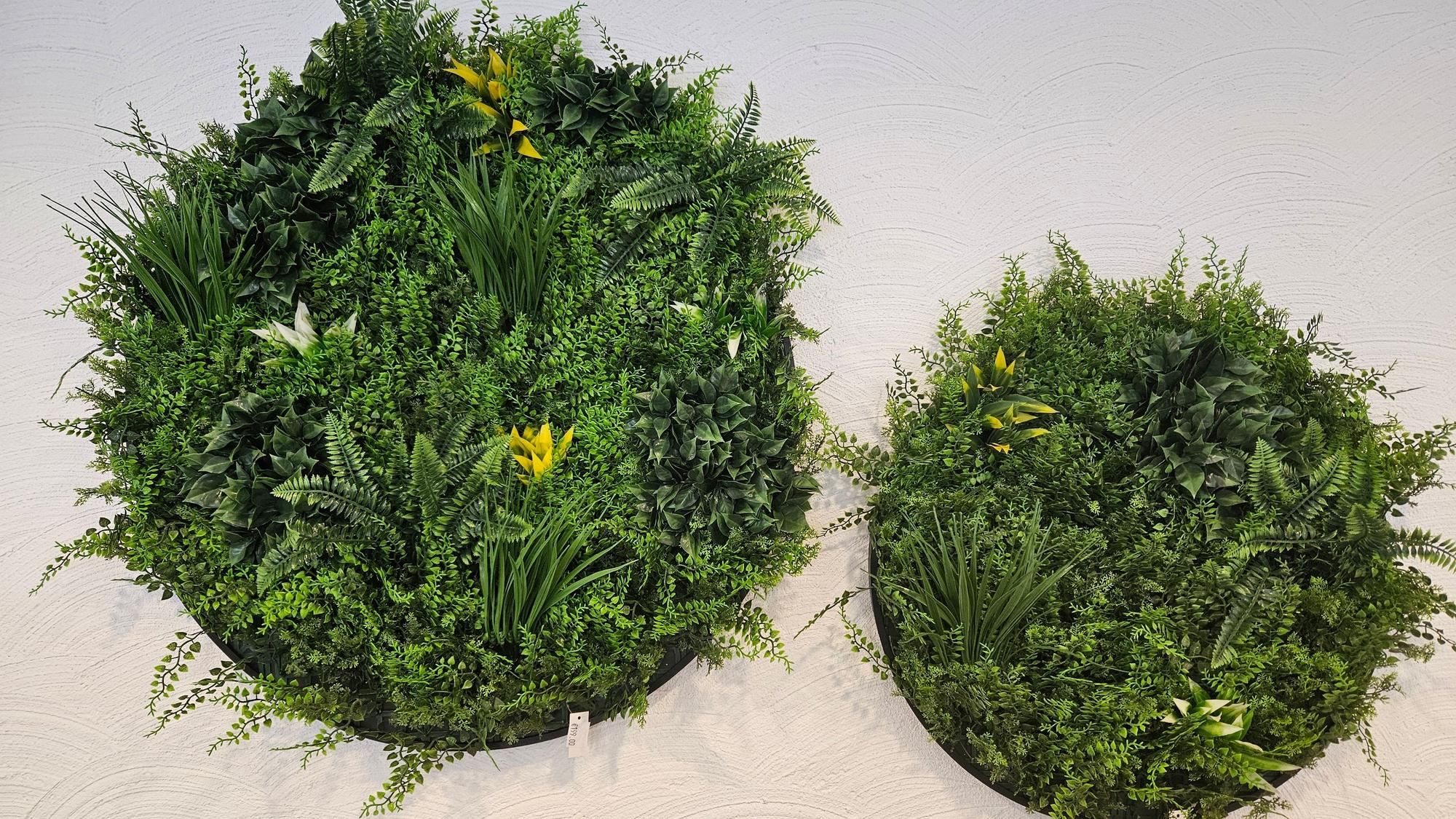 Blick auf zwei Gestecke mit Kunstblumen, die im Café an einer Wand hängen.