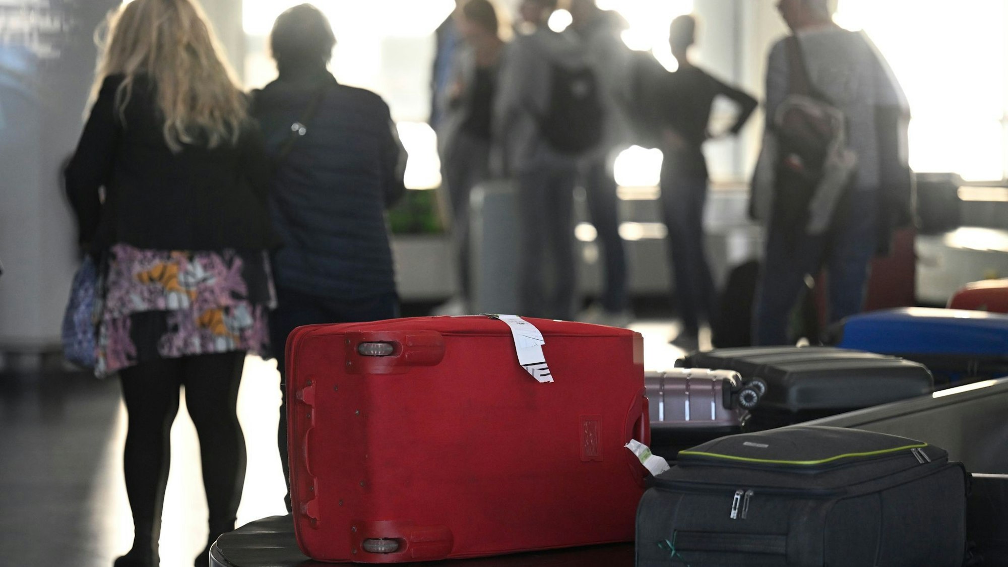 Passagiere warten am Gepäckband auf ihre Koffer